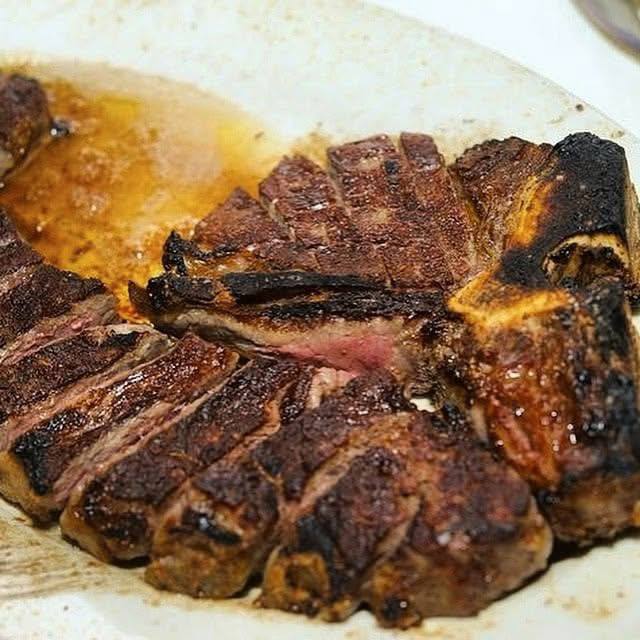 USDA Prime strip steak, charcoal-broiled and sliced tableside